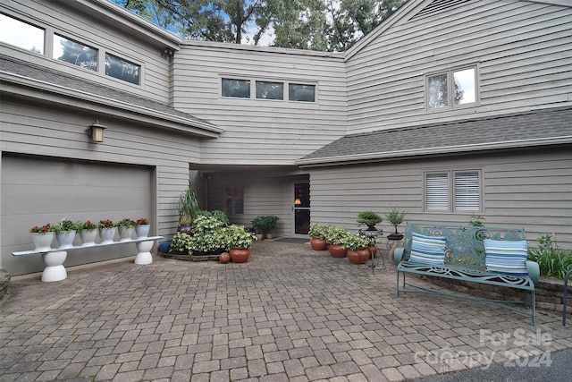 entrance to property featuring a garage and a patio area