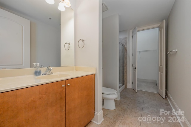 bathroom featuring tile patterned flooring, vanity, toilet, and a shower with shower door