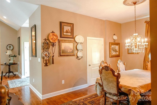 dining area with lofted ceiling, wood-type flooring, and a notable chandelier