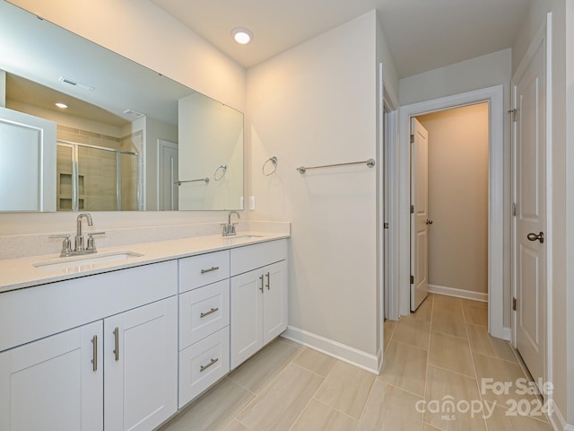 bathroom with tile patterned floors, a shower with door, and vanity