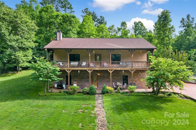 view of front of home featuring a patio area, a chimney, brick siding, and a front yard