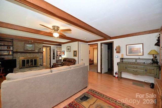 living room featuring ceiling fan, wood-type flooring, a fireplace, and beamed ceiling