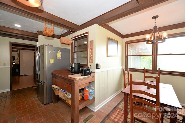 kitchen with wood counters, an inviting chandelier, stainless steel fridge, pendant lighting, and beamed ceiling