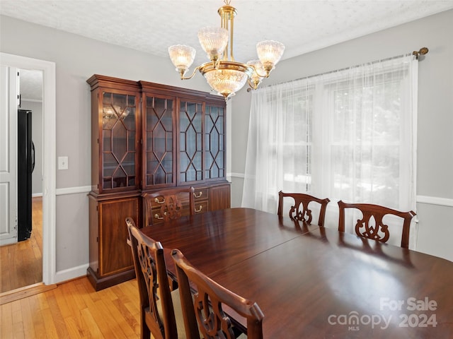 dining space featuring an inviting chandelier, a textured ceiling, and light hardwood / wood-style floors