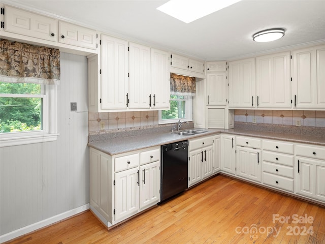 kitchen featuring dishwasher, a skylight, white cabinets, light wood-type flooring, and sink