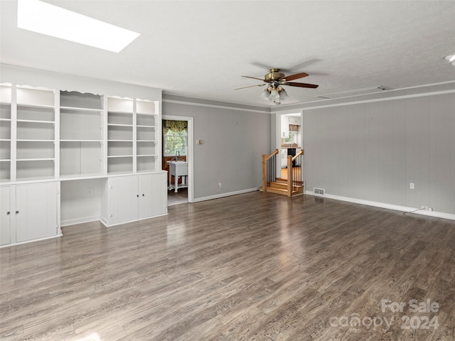 unfurnished living room with ceiling fan, a skylight, hardwood / wood-style floors, and a textured ceiling