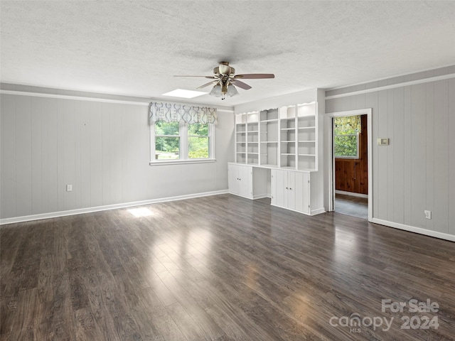 interior space featuring plenty of natural light, wooden walls, dark wood-type flooring, and ceiling fan