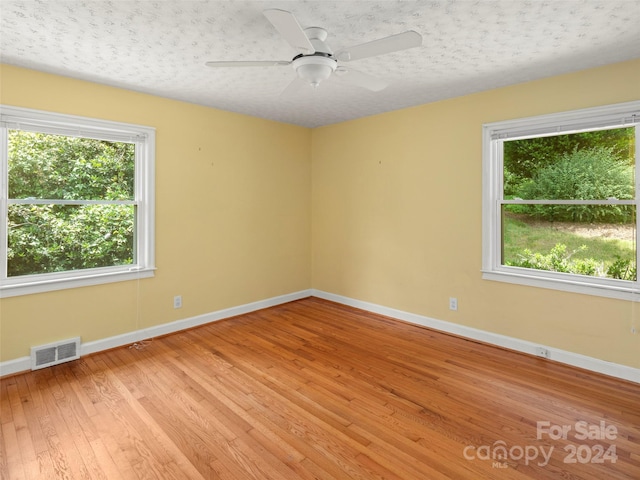 unfurnished room featuring light hardwood / wood-style floors, a textured ceiling, and ceiling fan