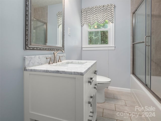 full bathroom featuring tile patterned floors, vanity, shower / bath combination with glass door, and toilet