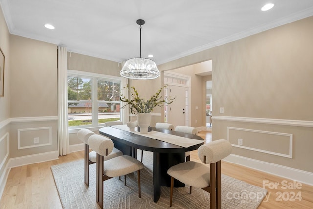 dining space featuring ornamental molding, a notable chandelier, and light wood-type flooring