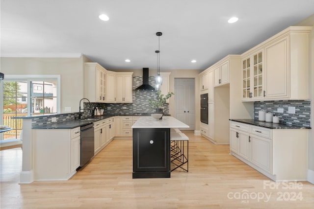 kitchen featuring black appliances, wall chimney range hood, pendant lighting, a kitchen island, and a breakfast bar area