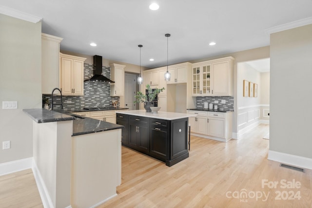 kitchen featuring decorative light fixtures, a kitchen island, tasteful backsplash, and wall chimney exhaust hood