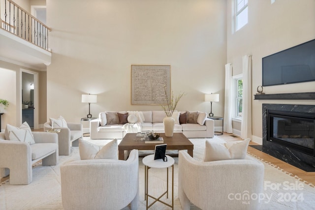 living room with light hardwood / wood-style floors, a fireplace, and a high ceiling