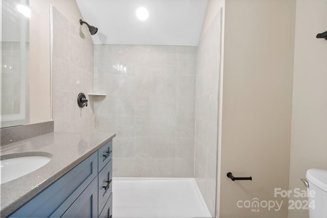 bathroom featuring tiled shower, vanity, and toilet