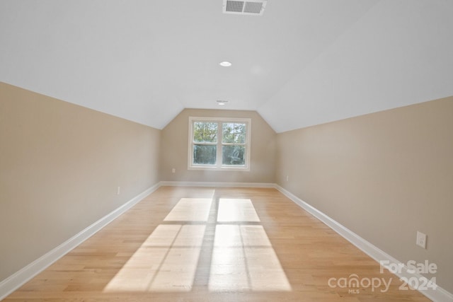 additional living space featuring light hardwood / wood-style floors and vaulted ceiling