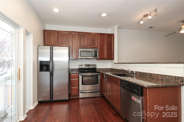 kitchen featuring dark wood-style flooring, stainless steel appliances, visible vents, a sink, and dark stone counters