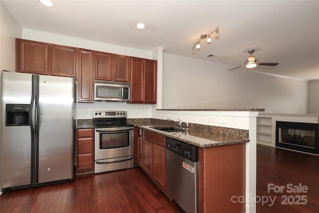 kitchen featuring a peninsula, dark wood-style flooring, stainless steel appliances, and a sink