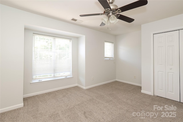 unfurnished bedroom featuring light carpet, baseboards, visible vents, and a closet