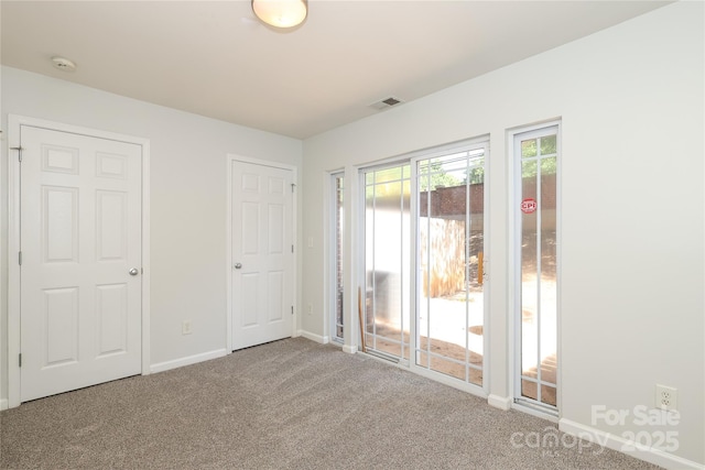 unfurnished room with carpet floors, visible vents, and baseboards