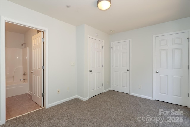unfurnished bedroom with tile patterned floors, baseboards, carpet flooring, and ensuite bathroom