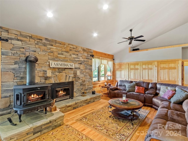 living room with lofted ceiling, ceiling fan, a fireplace, wood-type flooring, and a wood stove