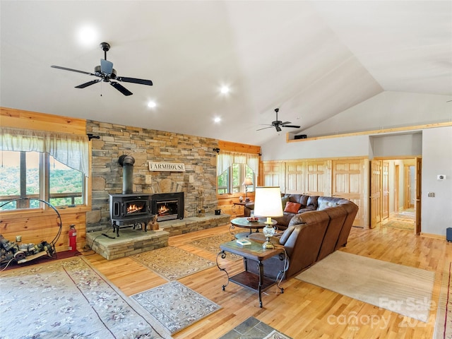 living room with hardwood / wood-style flooring, a wood stove, lofted ceiling, and ceiling fan