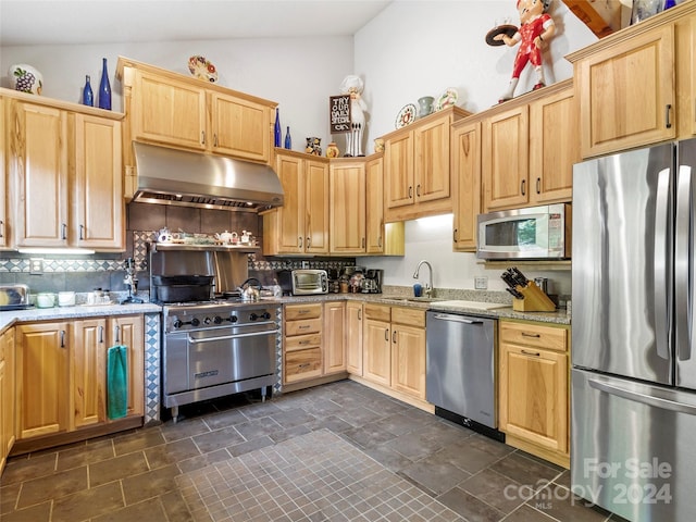 kitchen featuring lofted ceiling, sink, stainless steel appliances, ventilation hood, and light stone counters