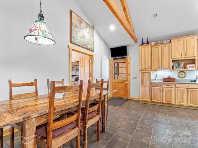 kitchen featuring decorative light fixtures, lofted ceiling with beams, and light brown cabinets