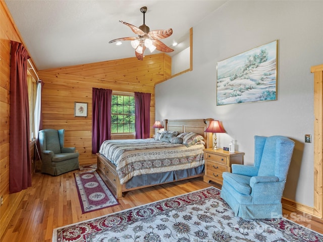 bedroom with ceiling fan, wood walls, lofted ceiling, and light wood-type flooring