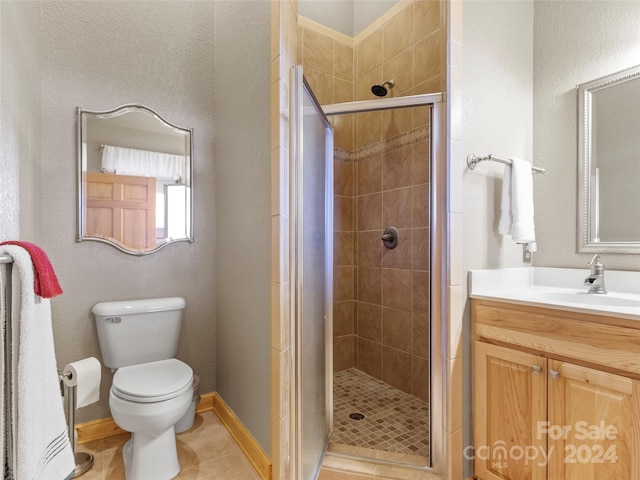 bathroom featuring a shower with shower door, toilet, vanity, and tile patterned flooring