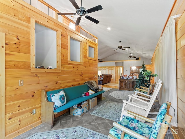 interior space with lofted ceiling, tile patterned flooring, a ceiling fan, and wooden walls