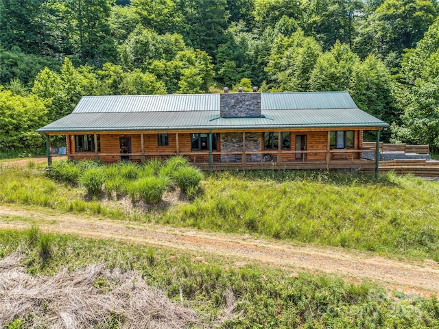 view of front of house featuring covered porch, metal roof, and a wooded view