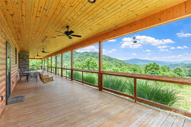 wooden deck featuring ceiling fan, a forest view, and a mountain view