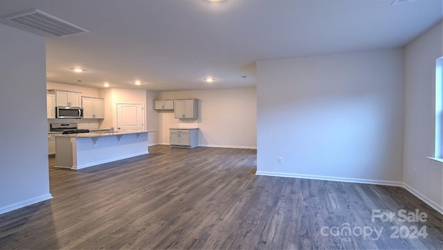 kitchen featuring a kitchen breakfast bar, dark hardwood / wood-style flooring, appliances with stainless steel finishes, and an island with sink