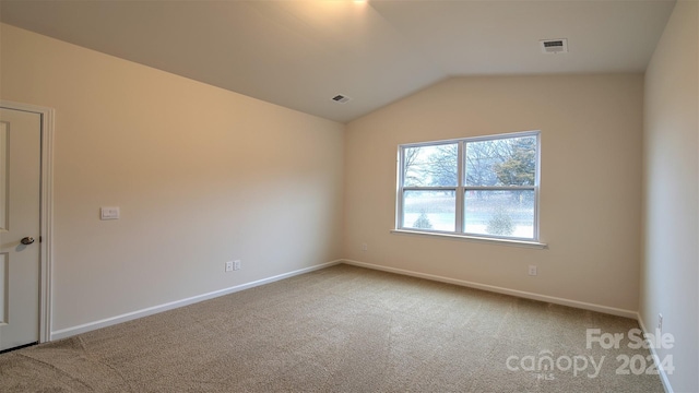 carpeted empty room with lofted ceiling