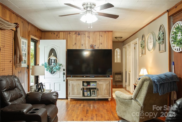 living room with ceiling fan, wooden walls, crown molding, and hardwood / wood-style flooring