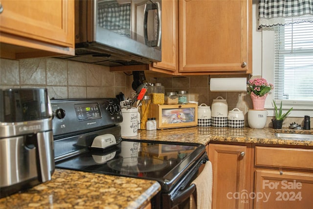 kitchen with black range with electric cooktop, plenty of natural light, backsplash, and stone countertops