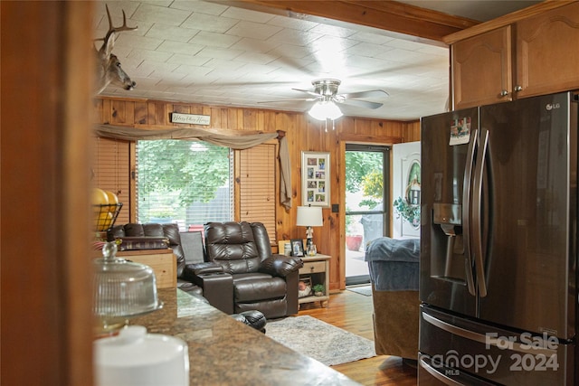 living room featuring ceiling fan, wood walls, and light wood-type flooring