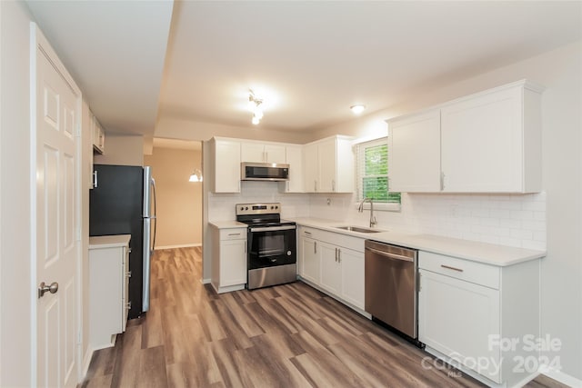 kitchen featuring backsplash, sink, hardwood / wood-style flooring, white cabinetry, and stainless steel appliances