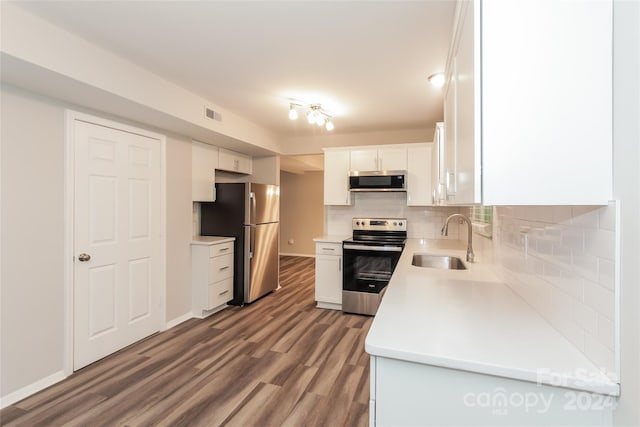 kitchen with white cabinetry, sink, backsplash, hardwood / wood-style floors, and appliances with stainless steel finishes