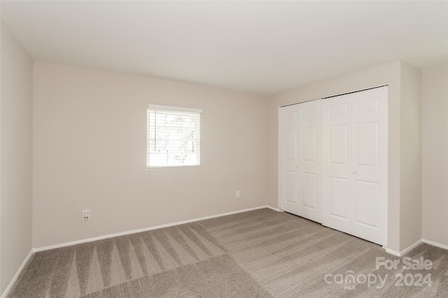 unfurnished bedroom with a closet and light colored carpet