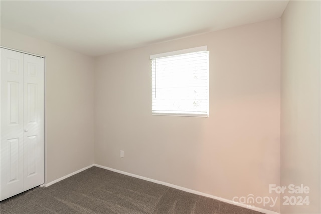 unfurnished bedroom featuring dark carpet and a closet