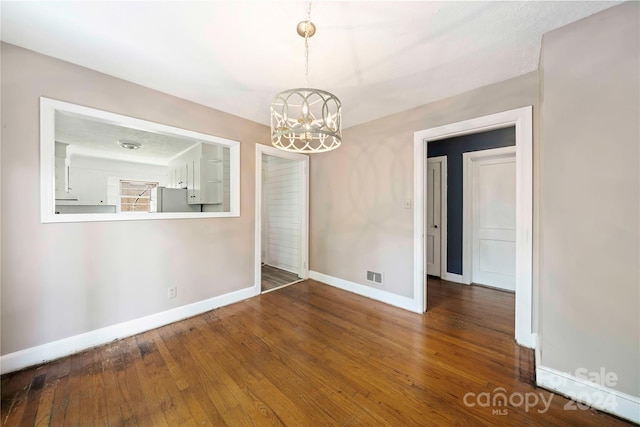 unfurnished dining area featuring hardwood / wood-style flooring and an inviting chandelier