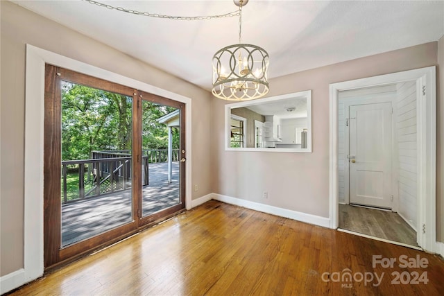 unfurnished dining area featuring hardwood / wood-style floors and an inviting chandelier