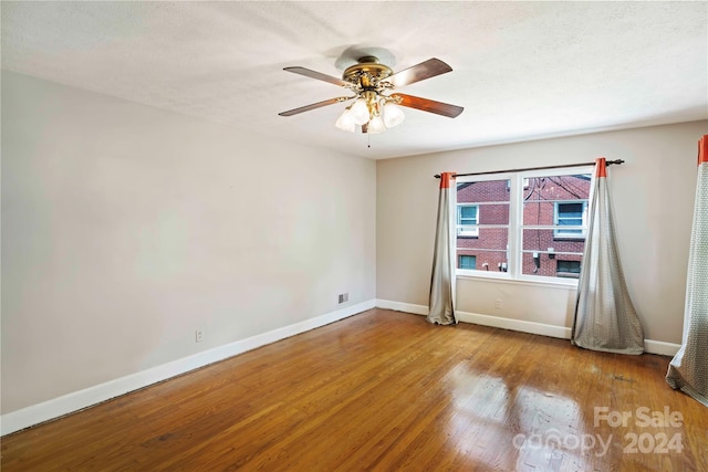 spare room featuring ceiling fan, wood-type flooring, and a textured ceiling