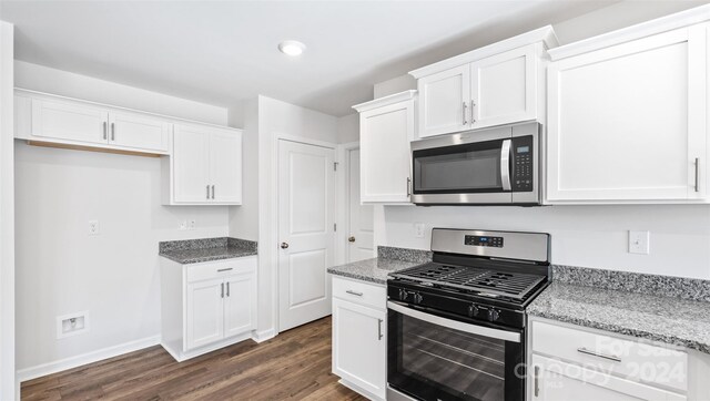 kitchen with light stone countertops, white cabinetry, dark hardwood / wood-style flooring, and stainless steel appliances