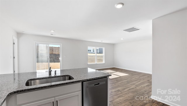 kitchen featuring dishwasher, dark hardwood / wood-style floors, dark stone countertops, and sink