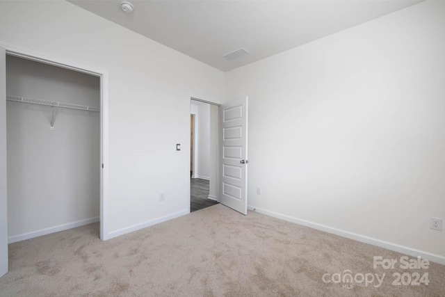 unfurnished bedroom with light carpet and a closet