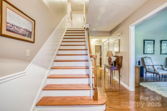 staircase featuring wood-type flooring and a textured ceiling