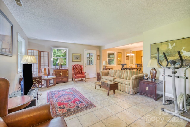 living room featuring a chandelier, a textured ceiling, and light tile patterned floors